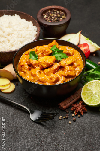 Plate of Traditional Chicken Curry and spices on dark concrete background
