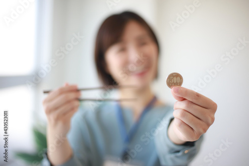 500円硬貨と箸を持つ女性社員 ワンコインランチイメージ