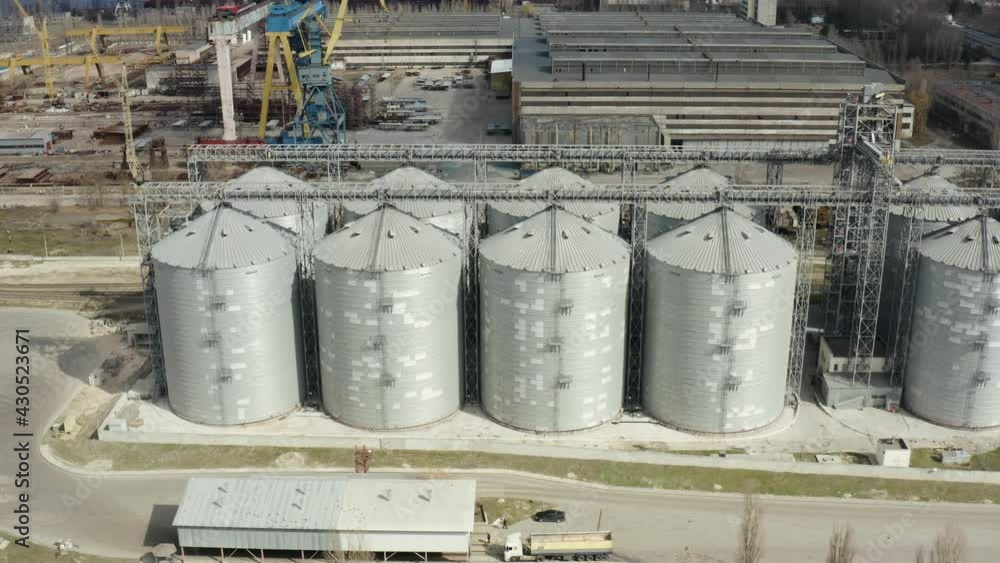 Grain elevator and silos near the river aerial view. Aerial view large waterfront grain storage facility with concrete silos and train yard. Grain elevator and silos near the river aerial view. Aerial view large waterfront grain storage facility with concrete silos and train yard.