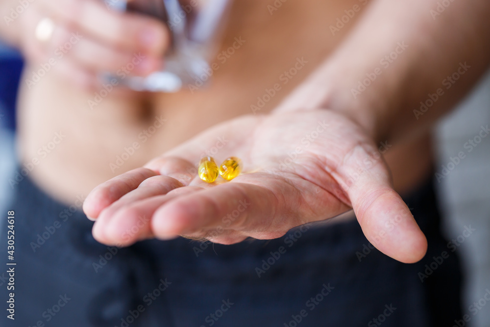 A young man holds vitamins and a glass of water in his hands. Immunity pills A young man holds vitamins and a glass of water in his hands. Immunity pills