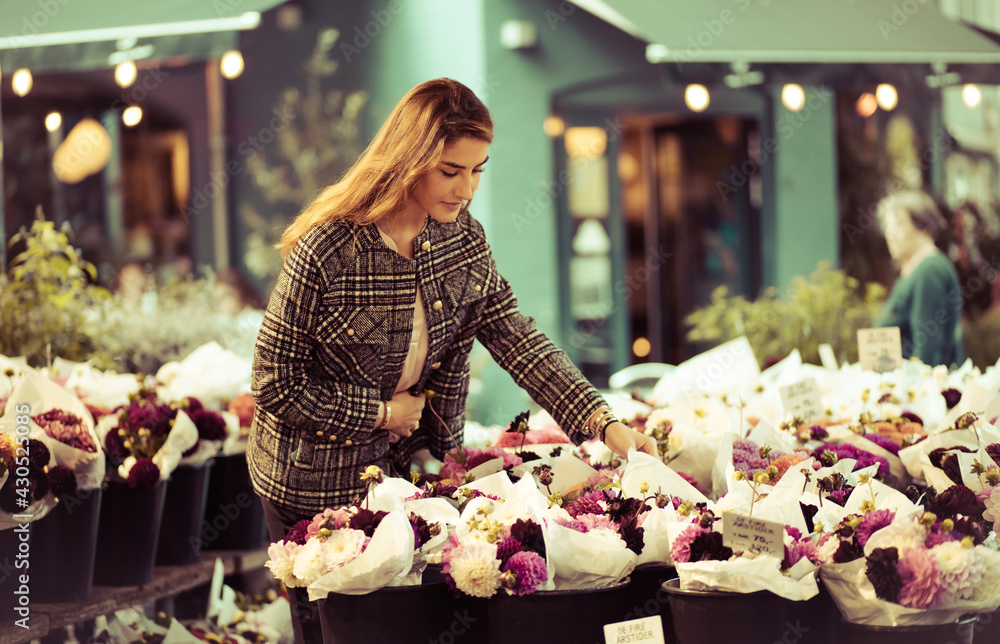 Woman in a flower shop chooses flowers.