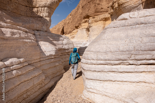 View inside a dry wadi Daras in a remote desert of the Northern Negev. Impressive white walls of a narrow winding canyon. Female hiker on a hiking trail in a heart of the desert. Nature reserve. photo