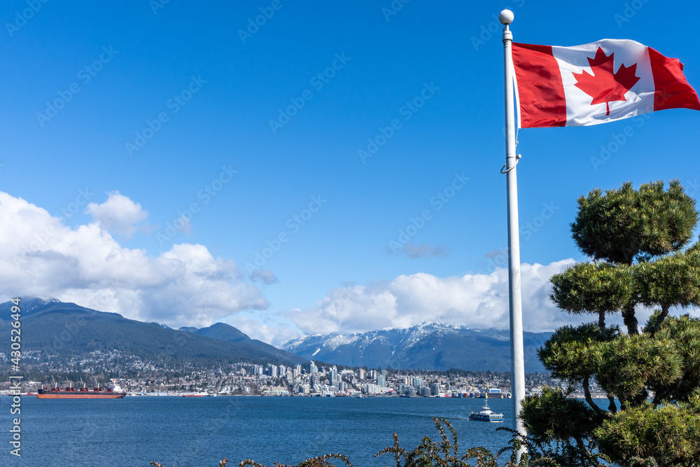 National Flag of Canada with North Vancouver City buildings in the background. Concept of canadian urban city life.