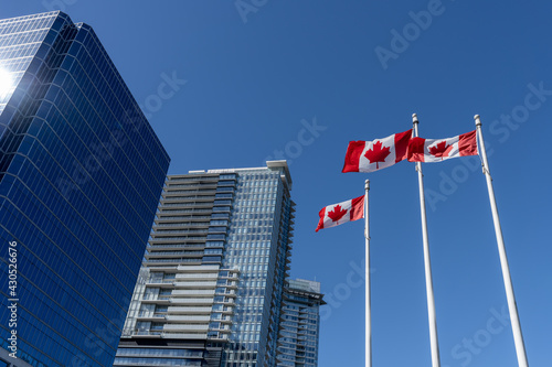 National Flags of Canada and Vancouver City skyscrapers skyline in the background. Concept of canadian urban city life.