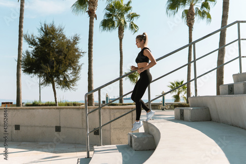 Athletic woman is running on concrete stairs during her summer workout © blackday