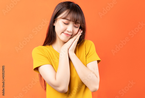 Image of young Asian woman wearing yellow t-shirt on orange background