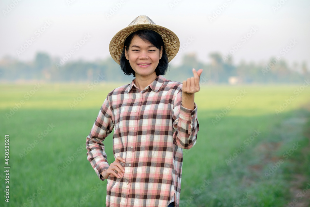 Asian farmer woman smile and pose hand mini heart sign at a green rice farm
