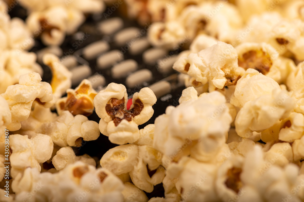 Popcorn scattered on the table and a remote control from the TV. Self-isolation in the covid-19 pandemic. Popcorn scattered on the table and a remote control from the TV. Self-isolation in the covid-19 pandemic.