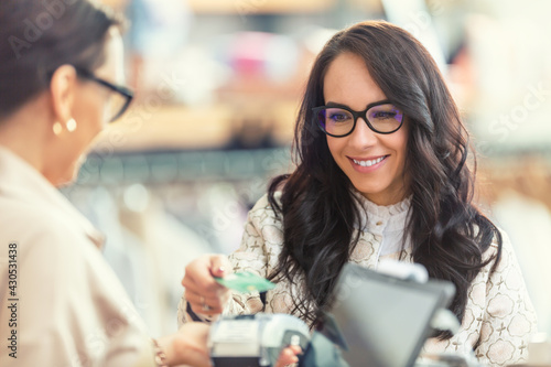 Female customer using card payment to pay in the garment boutique to the shop assistant photo