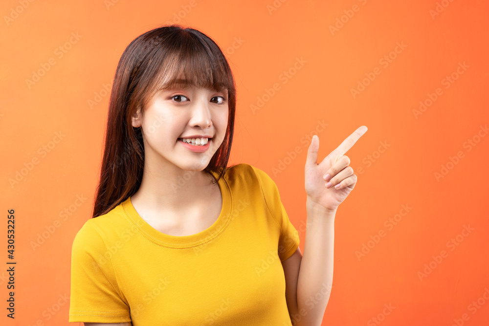 Image of young Asian girl wearing yellow t-shirt on orange background Image of young Asian girl wearing yellow t-shirt on orange background