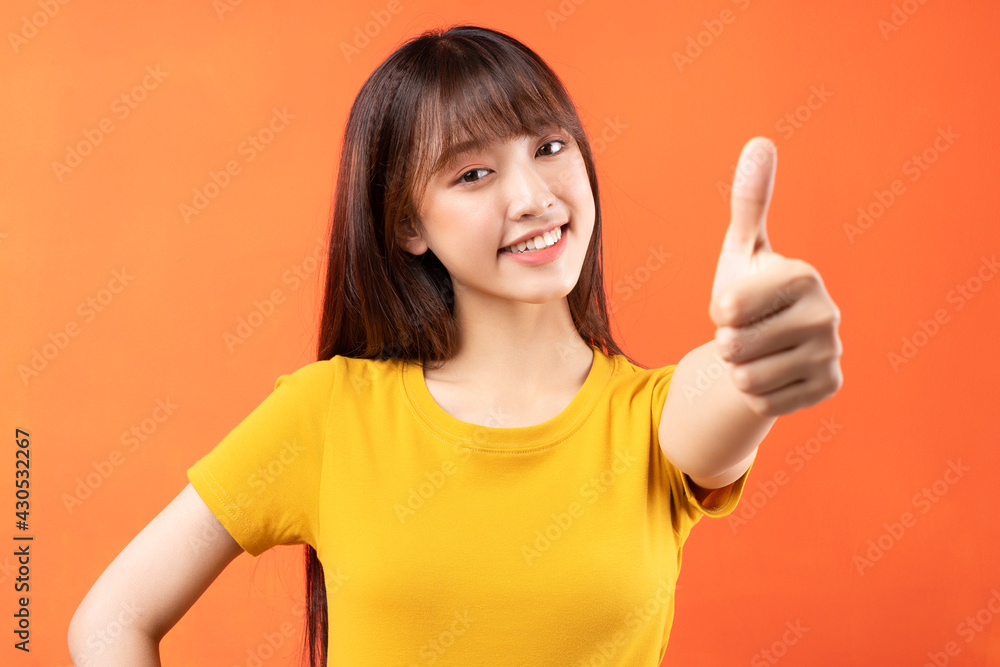 Image of young Asian girl wearing yellow t-shirt on orange background Image of young Asian girl wearing yellow t-shirt on orange background