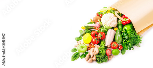 Healthy vegan food in full paper bag  vegetables and fruits on white background  copy space  banner. Shopping food  supermarket  groceries and clean eating concept