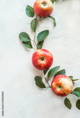Fresh red apples with green leaves on white desk background. Top view