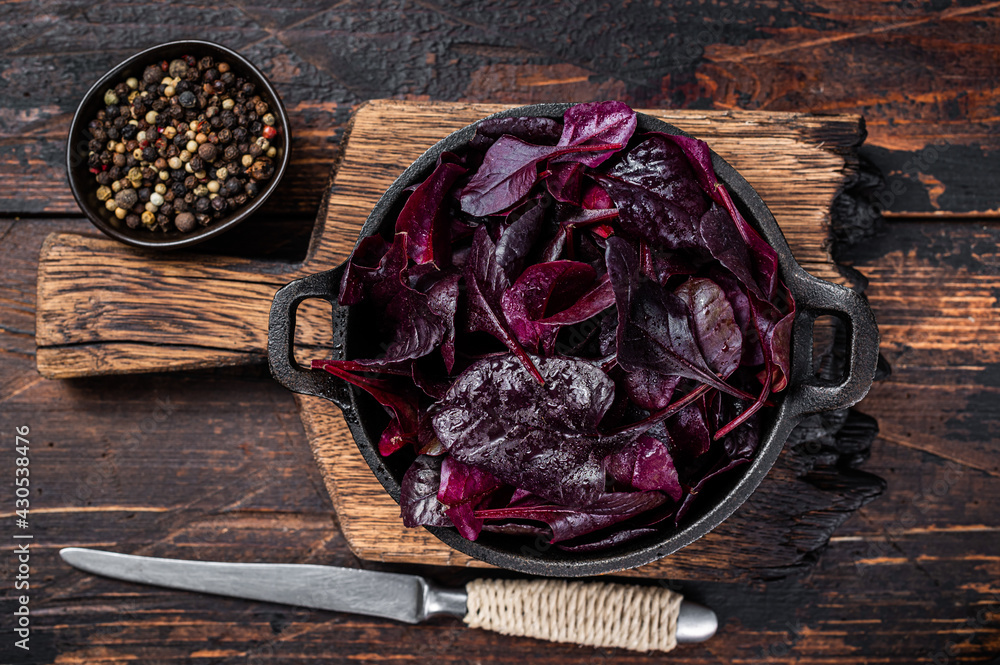 Swiss red chard or Mangold salad Leafs in a pan. Dark wooden background. Top view