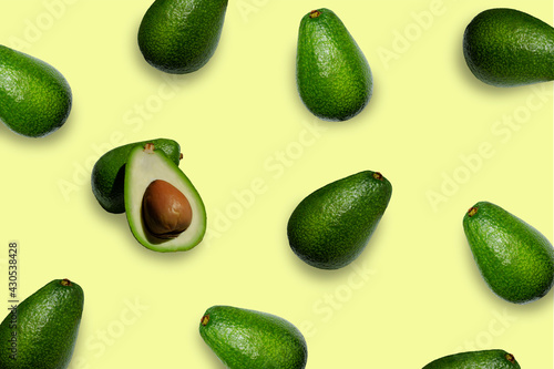 background with avocados scattered chaotically on a yellow background, top view