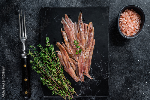 Anchovies fish fillet in Olive Oil. Black background. Top view