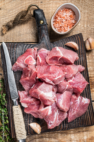 Fresh Raw Diced pork cubs meat with spices on a wooden butcher board. wooden background. Top view