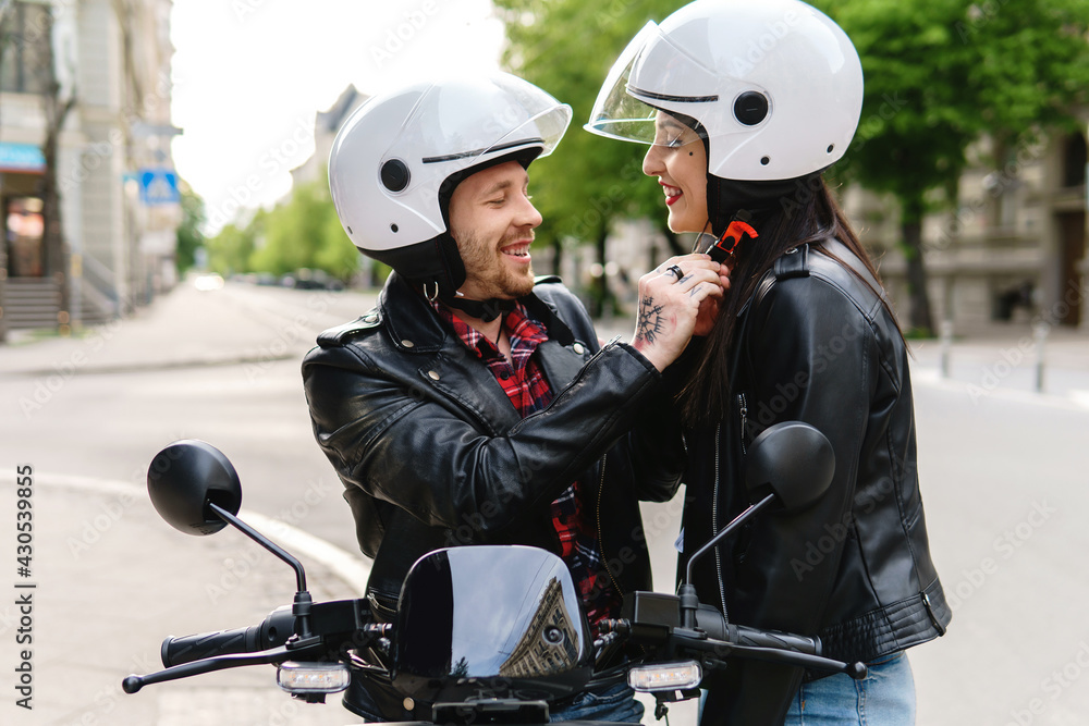 Stylish couple wearing motorcycle helmets before ride on electric scooter