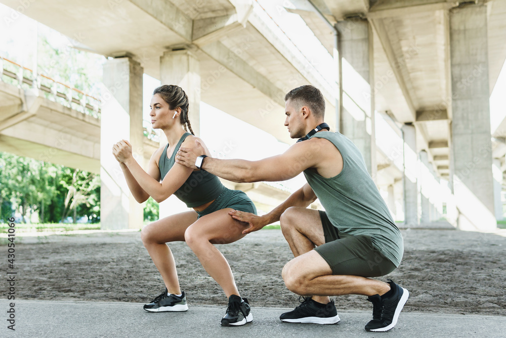 Athletic couple doing squats during street workout