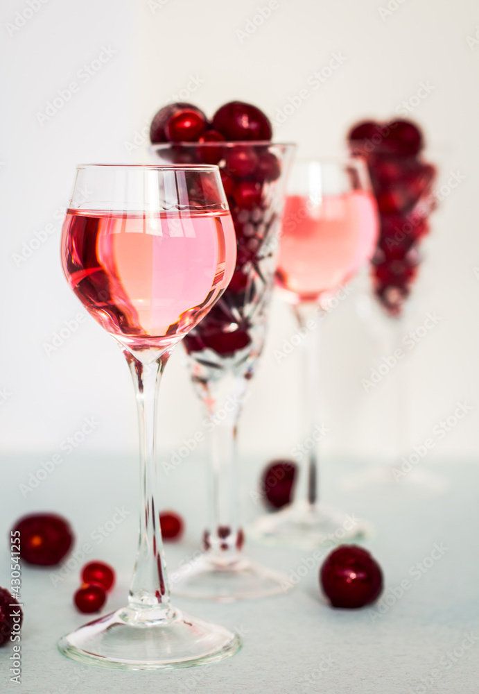 transparent glasses of pink gin infused with cranberry on light background, crystal glasses of spirits drinks with berries, a row of cherry liquor or any red alcoholic cocktail, minimalism transparent glasses of pink gin infused with cranberry on light background, crystal glasses of spirits drinks with berries, a row of cherry liquor or any red alcoholic cocktail, minimalism