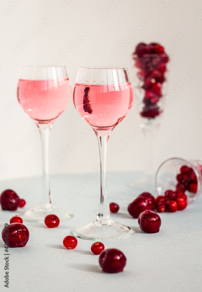 two glasses of pink gin or vodka infused with cranberry on light background, berry liquor or any alcohol cocktail among red berries, minimalism two glasses of pink gin or vodka infused with cranberry on light background, berry liquor or any alcohol cocktail among red berries, minimalism