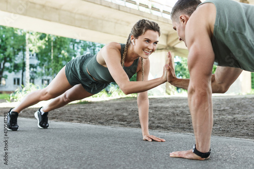 Athletic couple and fitness training outdoors. Man and woman doing push-ups exercise.