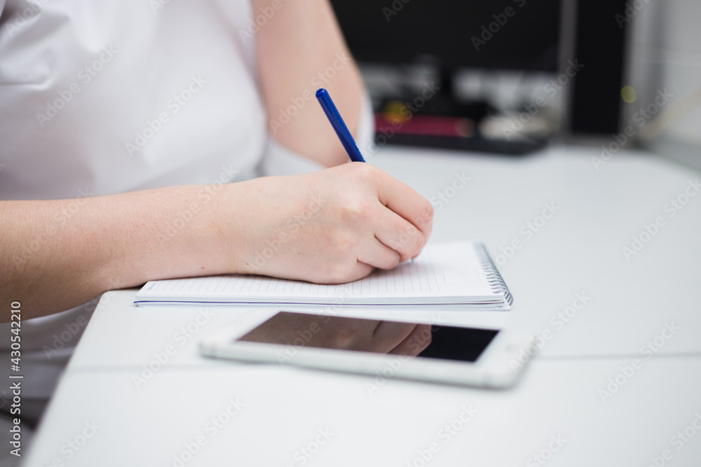 close-up of the doctor writing in a notebook at the desk in the office close-up of the doctor writing in a notebook at the desk in the office