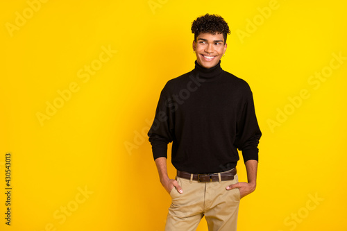 Photo of confident cute dark skin guy dressed black turtleneck arms pockets looking empty space isolated yellow color background