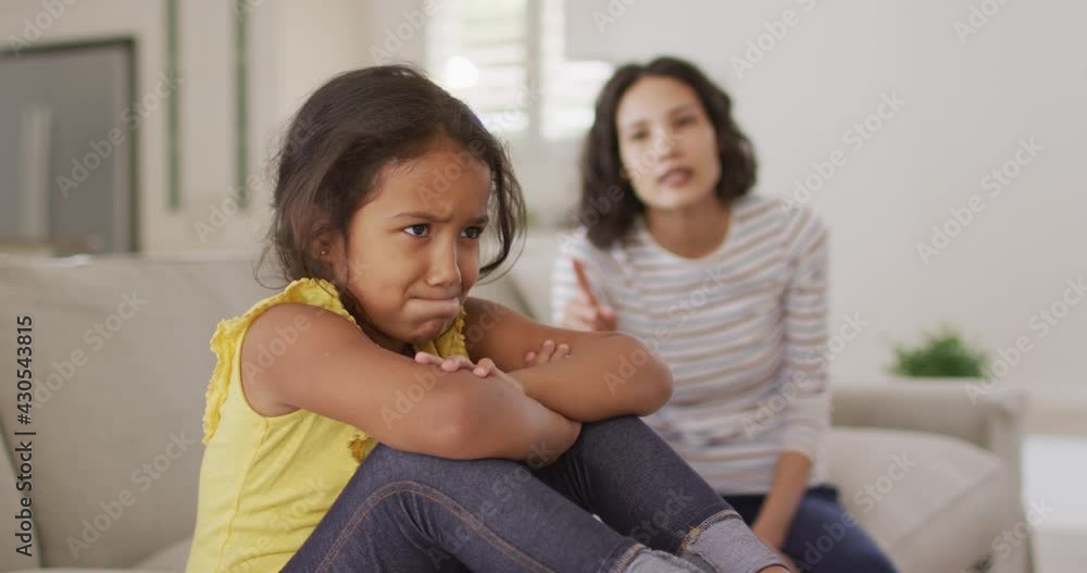 Angry hispanic mother telling off her young updet daughter sitting on sofa Angry hispanic mother telling off her young updet daughter sitting on sofa
