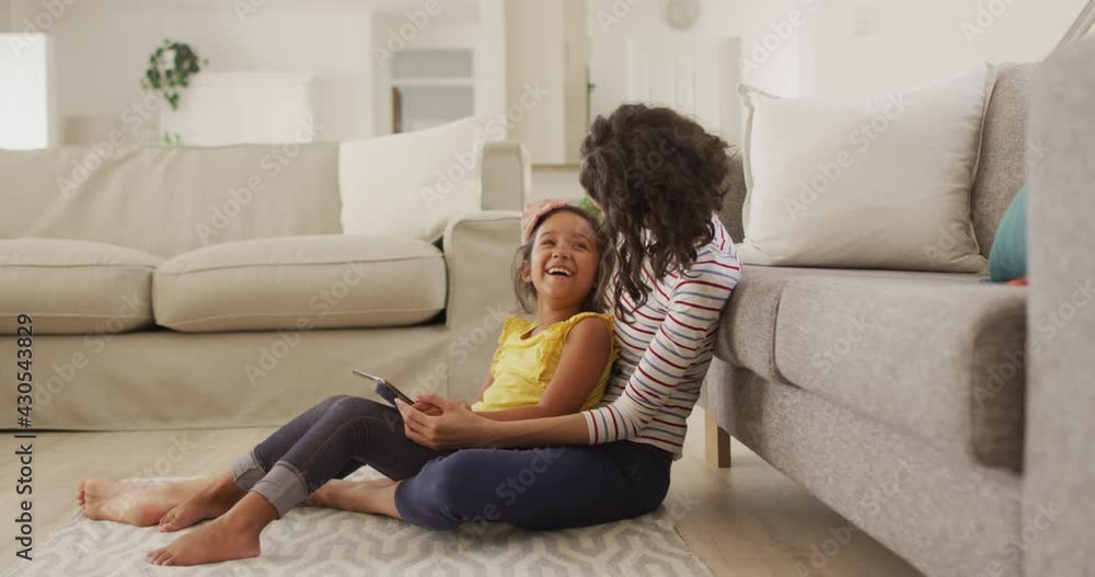 Happy hispanic mother and daughter sitting on floor using tablet Happy hispanic mother and daughter sitting on floor using tablet