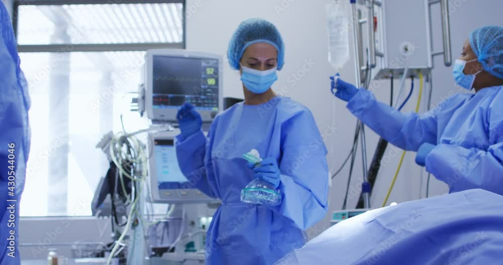 Diverse female surgeons wearing face masks and protective clothing during operation in hospital Diverse female surgeons wearing face masks and protective clothing during operation in hospital