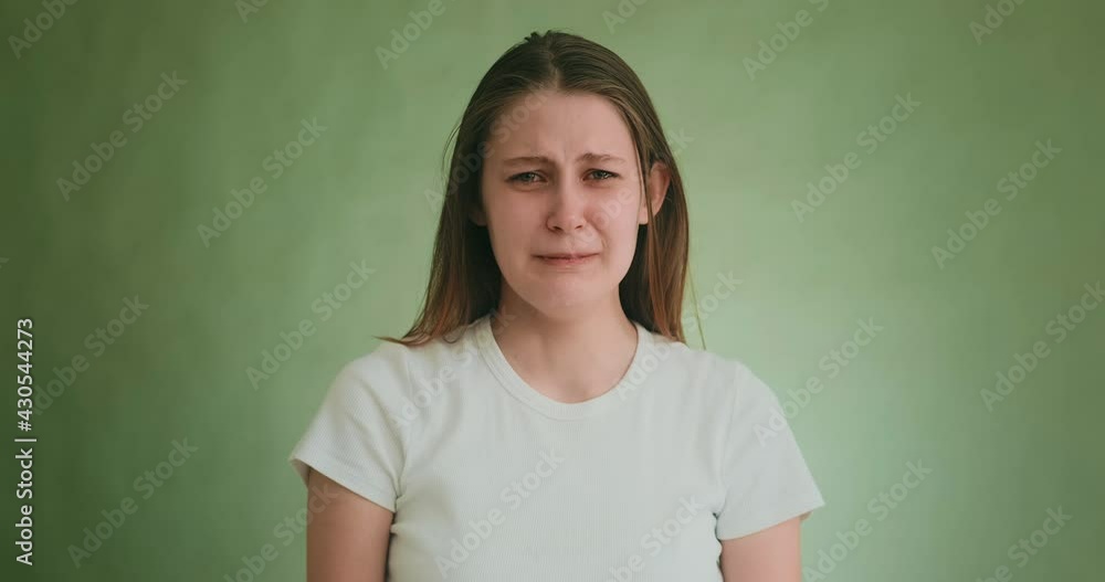 Stressed young woman in white clothes cries with offence posing for camera on green background at audition closeup slow motion Stressed young woman in white clothes cries with offence posing for camera on green background at audition closeup slow motion