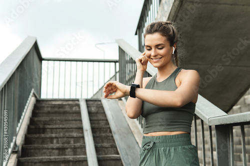 Tableau sur toile Athletic woman using smartwatch during her fitness workout on city street