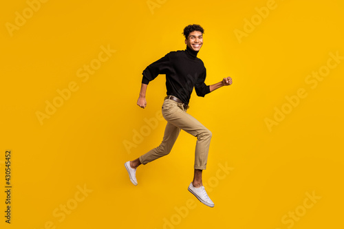 Photo of sweet pretty dark skin man wear black sweater eyewear running jumping isolated yellow color background