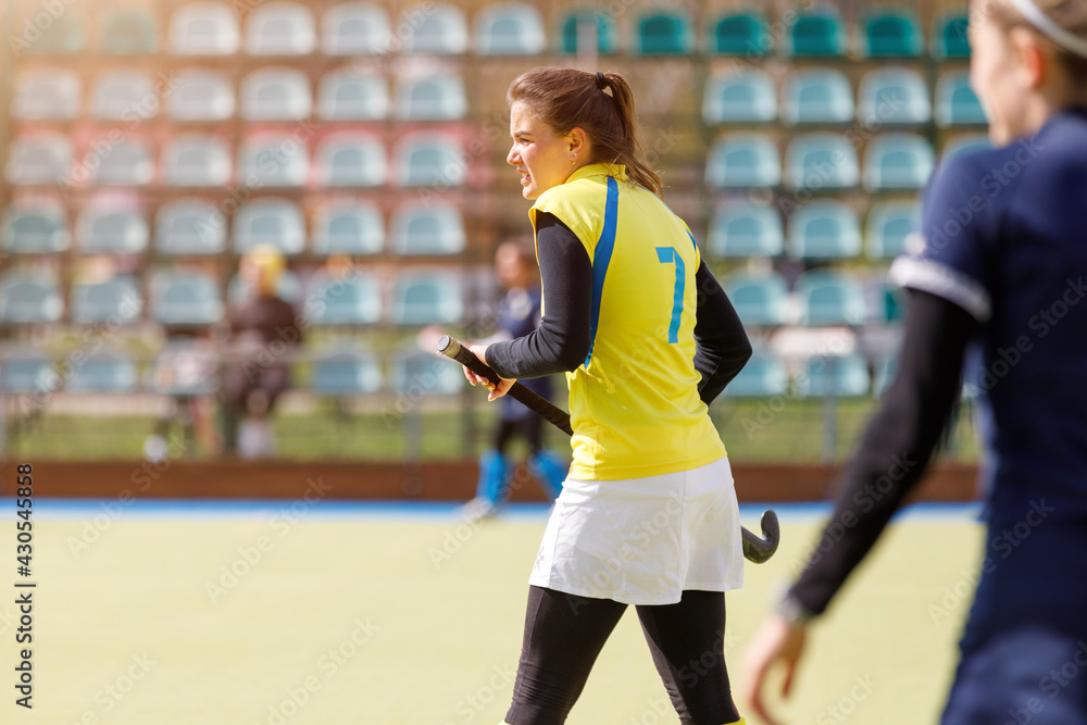 Young field hockey girl player with stick at pitch