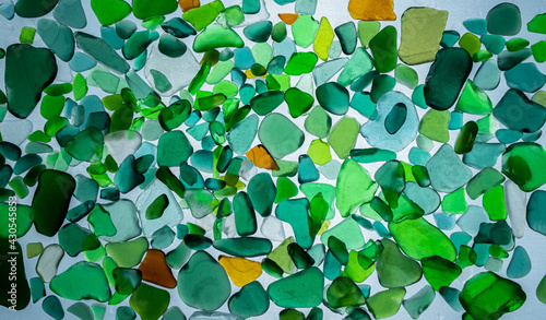 Summer background from sea glass top view. Broken glass from the ocean. Sea pattern. Oceanic mosaic. Natural colors of blue, green, white found on the coast