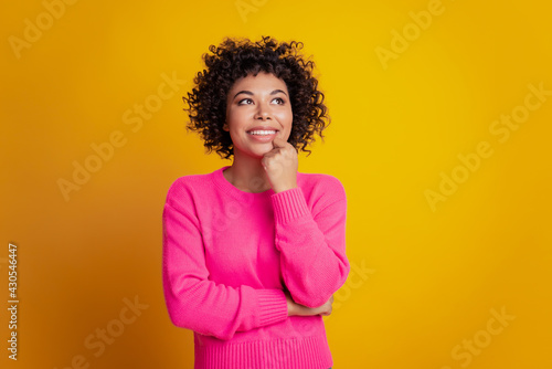 Portrait of dreamy smiling fashion girl look up blank space on yellow background