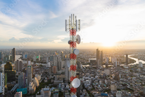 Telecommunication tower with 5G cellular network antenna on city sunset background photo