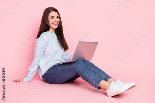Full size profile photo of nice optimistic brunette hairdo lady sit type laptop wear shirt jeans isolated on pink background