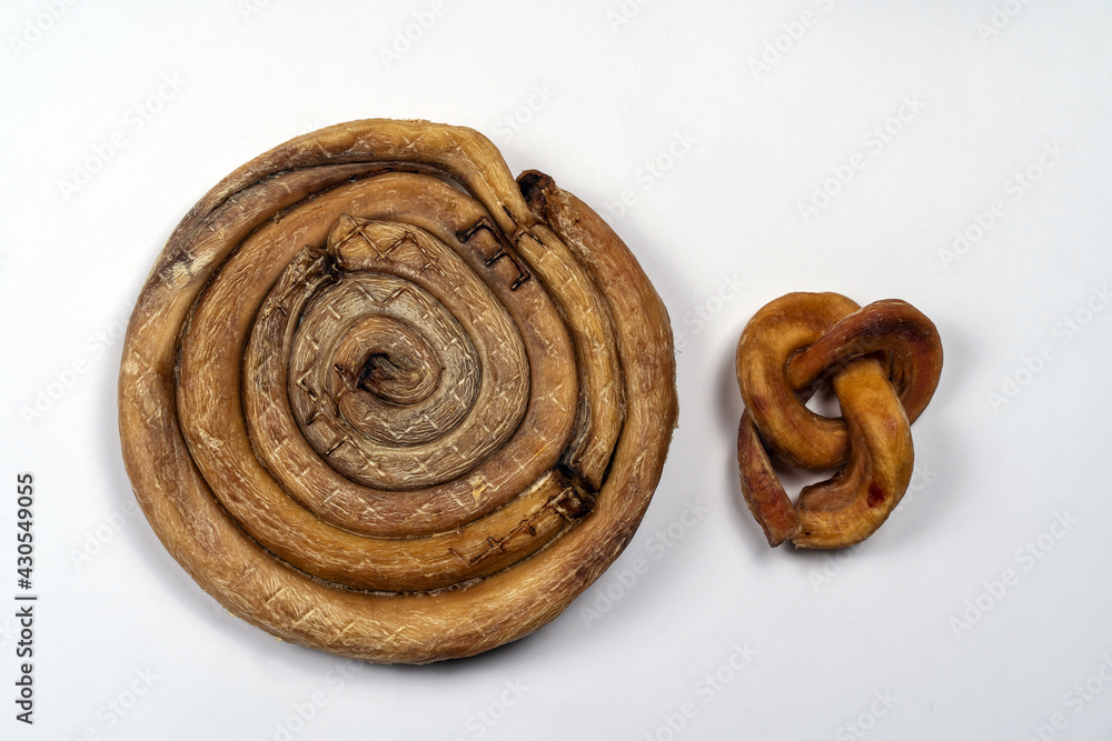 Two pieces pf dried beef pizzles, big and small one, on white background. Natural chewy dog treats, sophisticatedly wrapped. Dehydrated foods, bull penis. Copy space. Two pieces pf dried beef pizzles, big and small one, on white background. Natural chewy dog treats, sophisticatedly wrapped. Dehydrated foods, bull penis. Copy space.