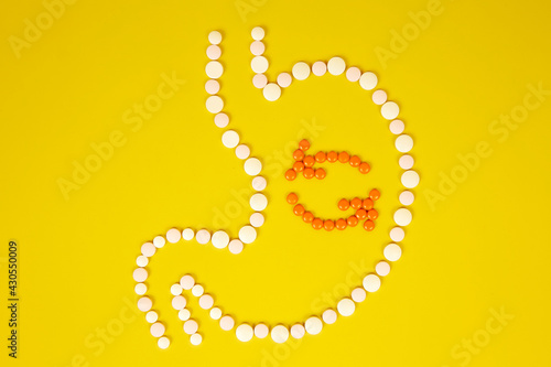 Human stomach from tablets, the process of digestion on a yellow background. The concept of healthy eating, metabolism in the body.