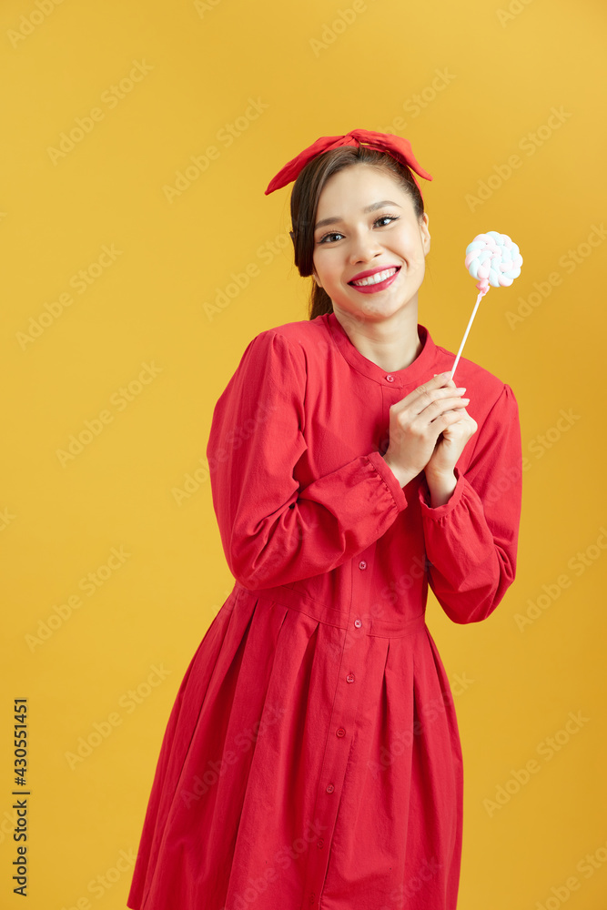 Young funky woman holding lollipop candy, looking away with dreamful smile as if making plans for party Young funky woman holding lollipop candy, looking away with dreamful smile as if making plans for party