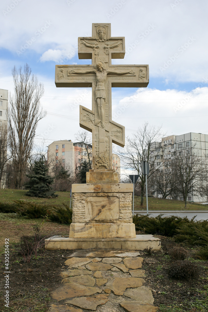 Cross Orthodox religion in front of a city. Stone monument of the Crucifixion of Christ.