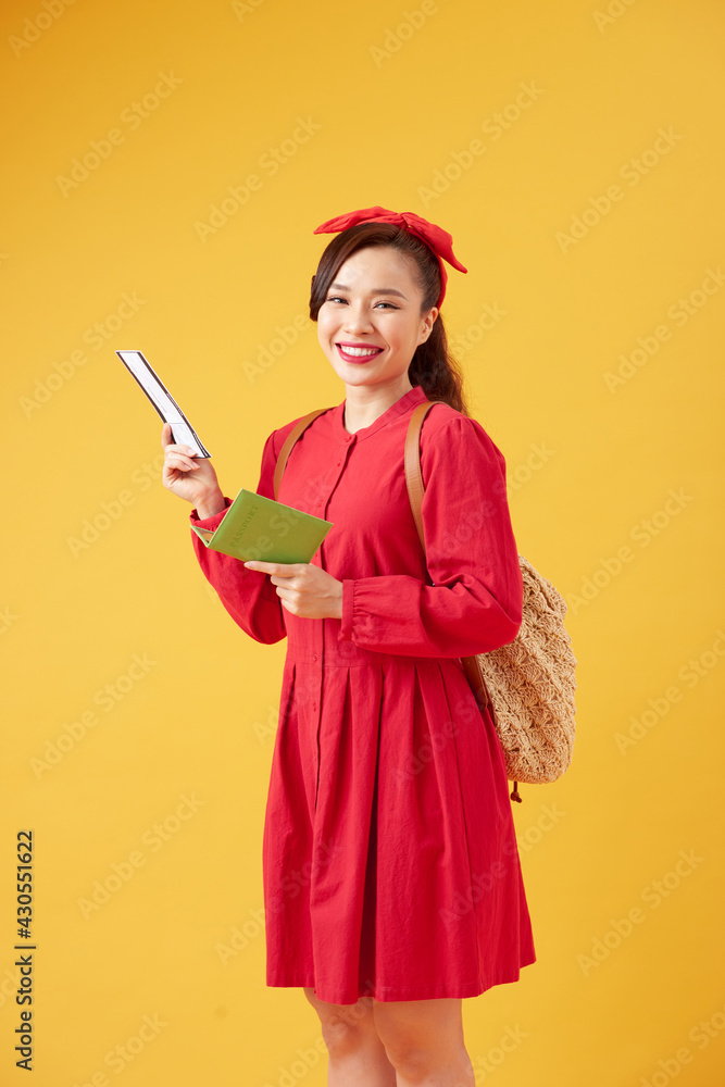 Smiling young woman tourist with backpack holding passport and flight tickets, yellow studio background Smiling young woman tourist with backpack holding passport and flight tickets, yellow studio background