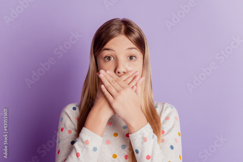 Young school girl cover mouth with palm isolated on purple background