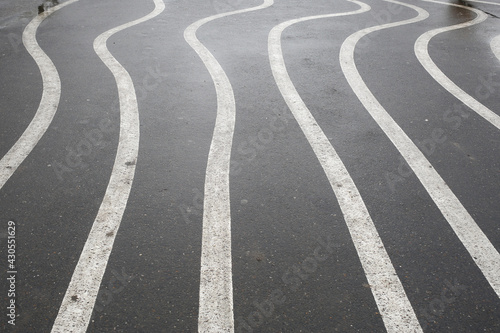 White zigzag stripes on the wet asphalt. © jonnyslav