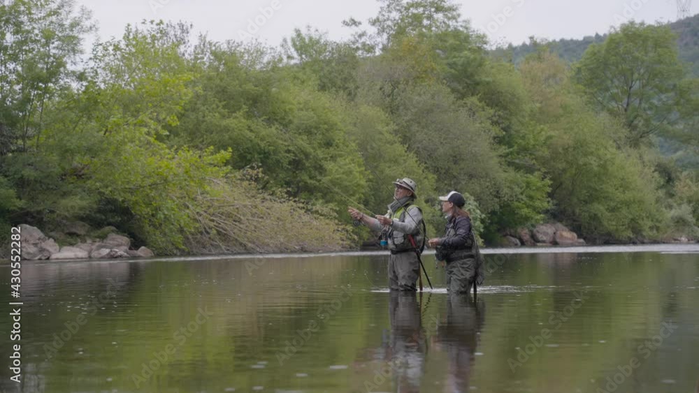 fishing guide with a young woman fly fishing for trout in a clear river fishing guide with a young woman fly fishing for trout in a clear river