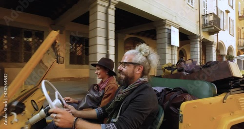 aerial view of man driving yellow car with his girlfriend next to him in a characteristic and desolated city in Italy