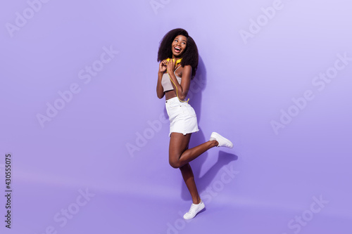 Full body profile side photo of young black girl happy smile headphones look empty space isolated over purple color background © deagreez