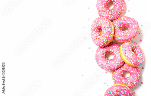 Amazing right donuts border. Top view of yummy fresh homemade doughnuts. Light background for you text. Decorated with confetti in shape of little hearts. 